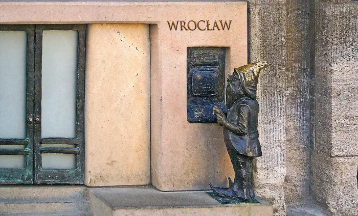 Figurka wrocławskiego krasnala wyciągającego środki z bankomatu.