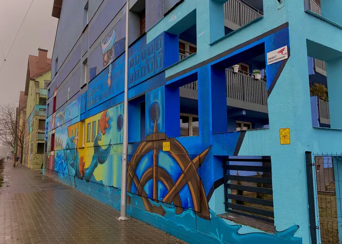 Kolorowy mural z motywem morskim na bloku mieszkalnym przy chodniku na osiedlu Księże