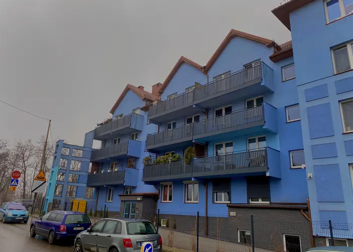 Ogrodzone niebieskie domy wielorodzinne z balkonami i czerwonym dachem