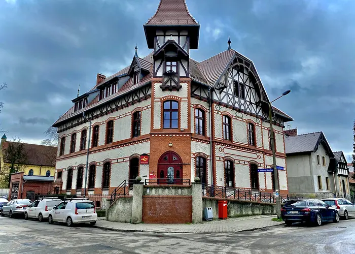 Ciekawy budynek na osiedlu Leśnica we Wrocławiu z ceglaną fasadą utrzymaną w kolorach białym i pomarańczowym. 