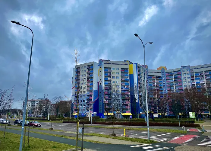 Bloki mieszkalne na osiedlu Picznyce-Kozanów-Popowice Północne. Przed blokami rozciąga się trawnik i ulica z przejściem dla pieszych i ścieżką rowerową.