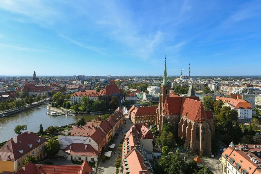 Panorama miasta z widokiem na rzekę i zróżnicowaną zabudowę, w tym kościół i inne zabytkowe budynki